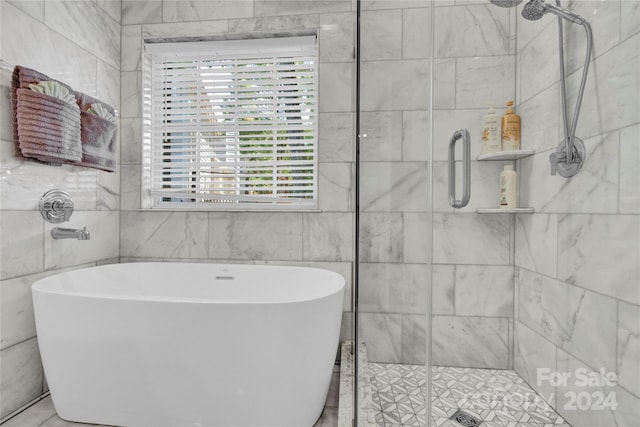 bathroom featuring plus walk in shower and tile walls