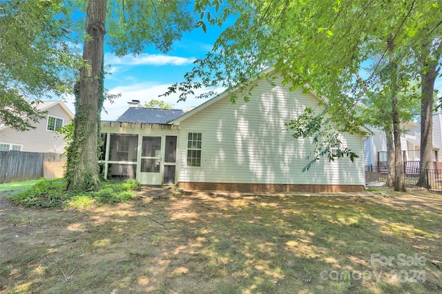 back of property featuring a sunroom and a yard