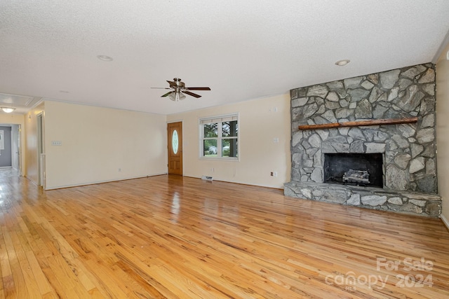 unfurnished living room with a fireplace, light hardwood / wood-style floors, a textured ceiling, and ceiling fan