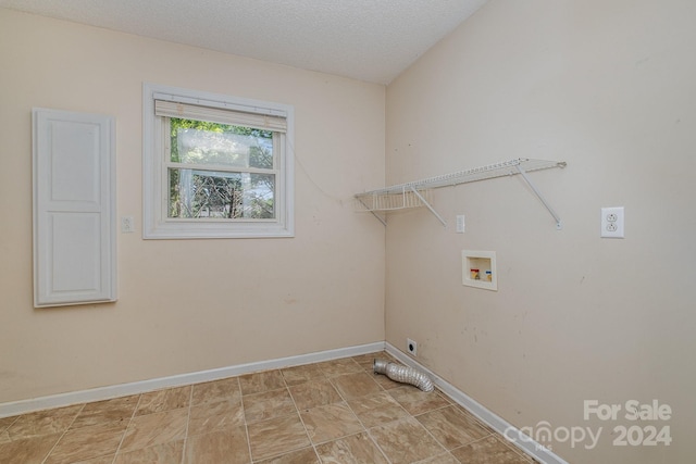 laundry room with hookup for a washing machine, a textured ceiling, and light tile patterned floors