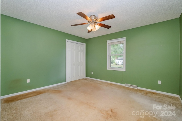 unfurnished room featuring a textured ceiling, ceiling fan, and light carpet