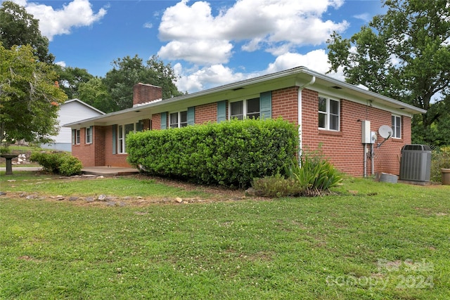 view of side of property with central AC unit and a lawn