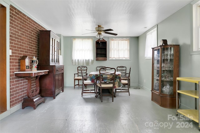 dining room with ceiling fan and brick wall