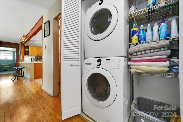 laundry area featuring stacked washing maching and dryer and light wood-type flooring