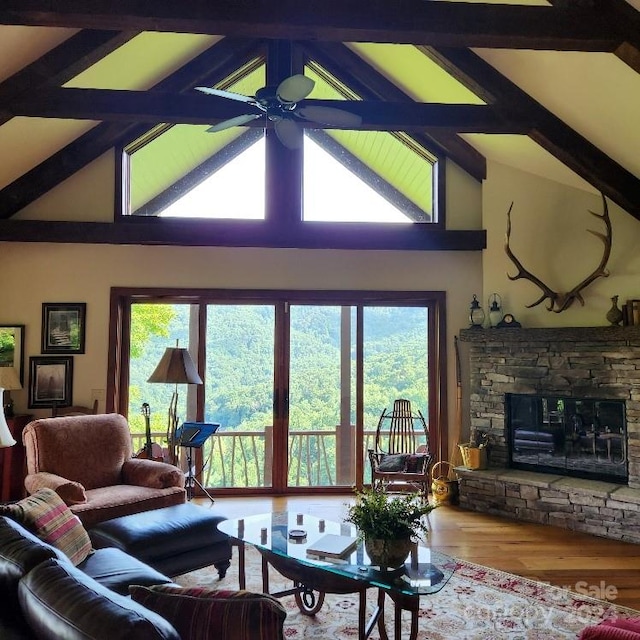 living room with ceiling fan, a wealth of natural light, beam ceiling, and a fireplace