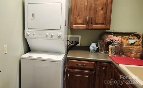 washroom featuring sink, stacked washer and clothes dryer, and cabinets