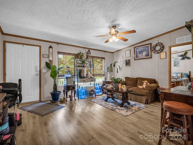 living room featuring ceiling fan, a textured ceiling, crown molding, and light hardwood / wood-style flooring