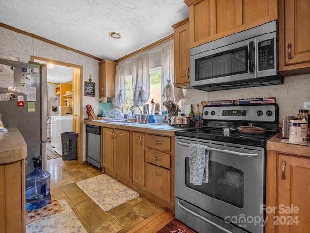 kitchen with a textured ceiling, crown molding, stainless steel appliances, sink, and light tile patterned flooring