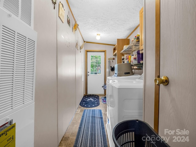 laundry area with a textured ceiling, washing machine and dryer, ornamental molding, and light tile patterned floors