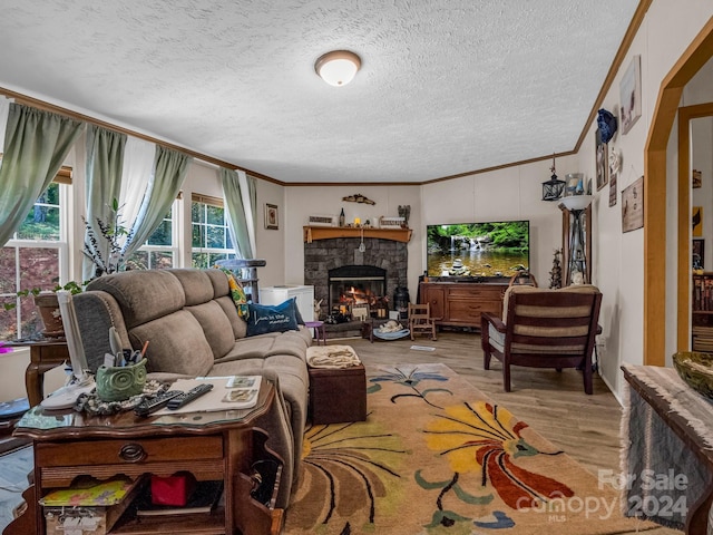 living room featuring a fireplace, a textured ceiling, ornamental molding, and light hardwood / wood-style flooring