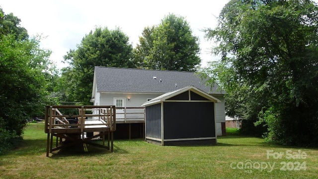 rear view of property with a lawn, a storage unit, and a deck