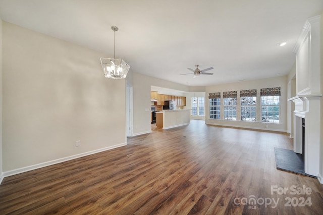 unfurnished living room featuring ceiling fan with notable chandelier and dark hardwood / wood-style flooring