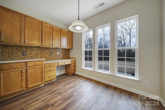 kitchen featuring pendant lighting, a wealth of natural light, built in desk, and tasteful backsplash