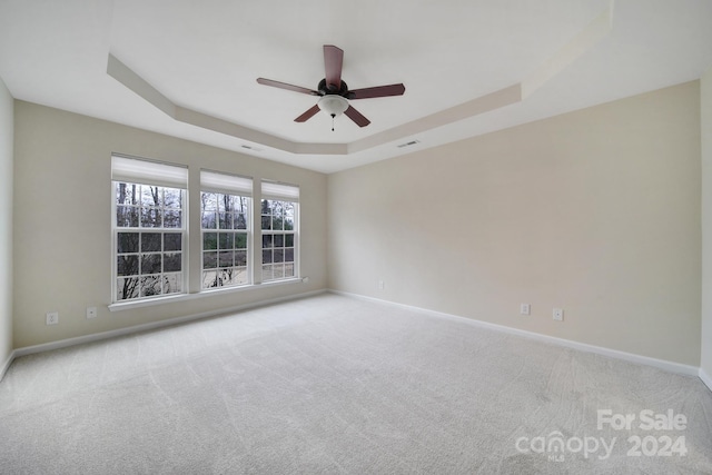 carpeted spare room featuring ceiling fan and a tray ceiling