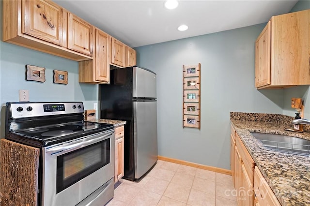 kitchen with sink, light brown cabinetry, appliances with stainless steel finishes, and dark stone countertops