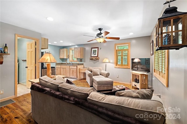 living room with light wood-type flooring, ceiling fan, and sink