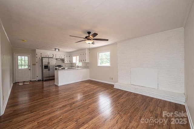 unfurnished living room featuring a textured ceiling, ceiling fan, sink, and dark hardwood / wood-style floors