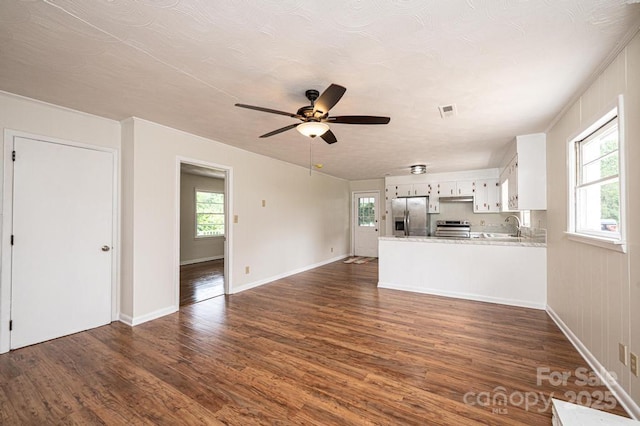 unfurnished living room with ceiling fan, sink, and dark wood-type flooring