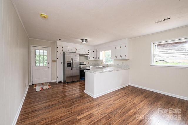 kitchen with white cabinets, appliances with stainless steel finishes, kitchen peninsula, and dark hardwood / wood-style floors