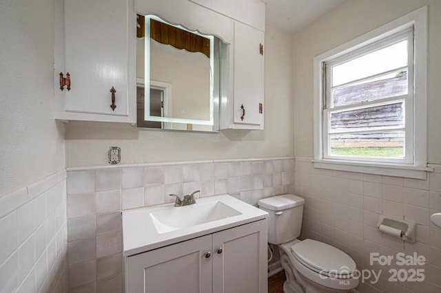 bathroom with vanity, toilet, and tile walls