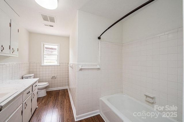 full bathroom with hardwood / wood-style floors, vanity,  shower combination, toilet, and tile walls