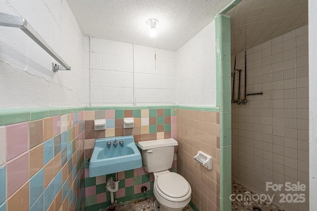 bathroom with a tile shower, a textured ceiling, and toilet