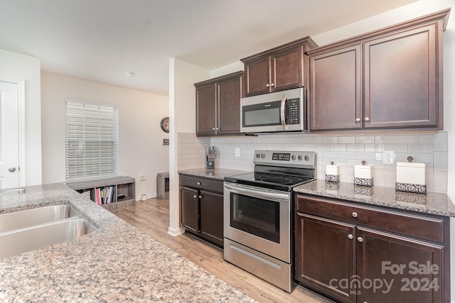 kitchen with sink, backsplash, dark brown cabinetry, light hardwood / wood-style floors, and stainless steel appliances