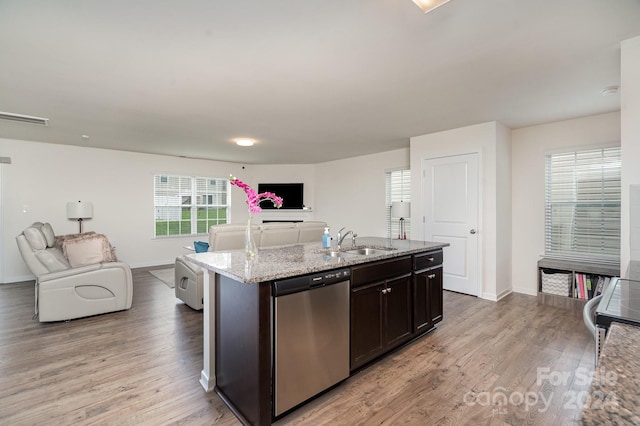 kitchen with an island with sink, sink, dark brown cabinetry, light hardwood / wood-style floors, and stainless steel appliances