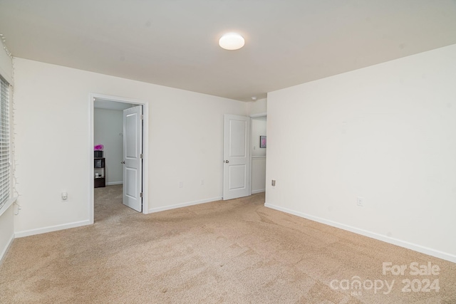 unfurnished bedroom with a spacious closet, light colored carpet, and a closet