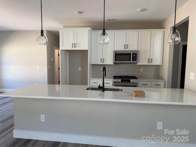 kitchen with decorative backsplash, dark wood-style flooring, stainless steel appliances, white cabinetry, and a sink