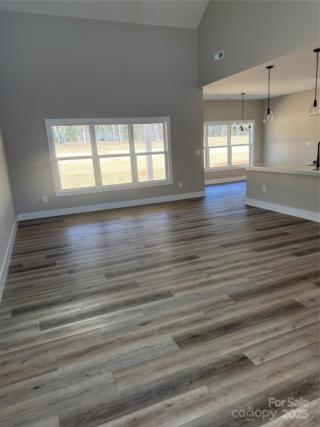 unfurnished living room featuring high vaulted ceiling, dark wood-style flooring, visible vents, and baseboards