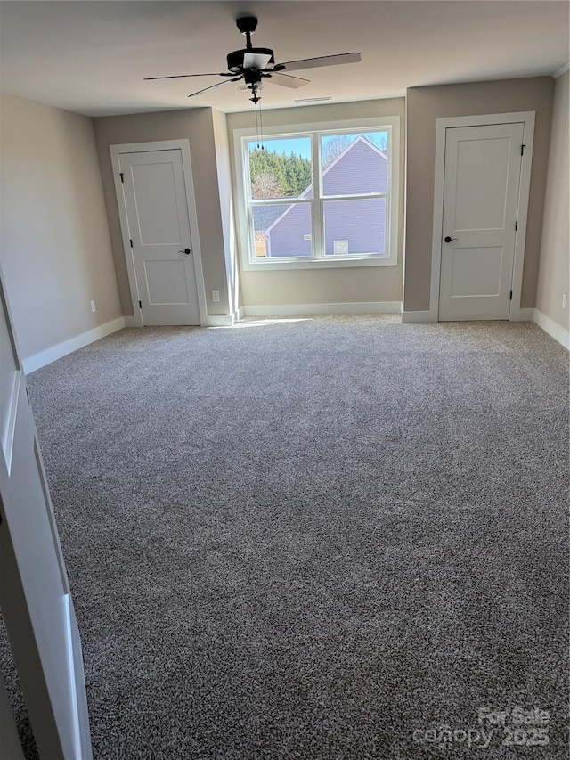 carpeted empty room with ceiling fan and baseboards