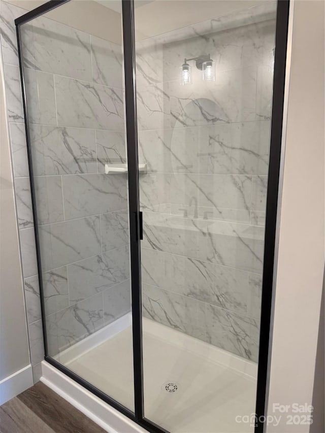 bathroom featuring wood finished floors and a shower stall