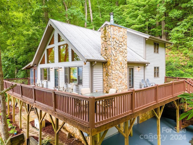 back of property with a view of trees and a wooden deck