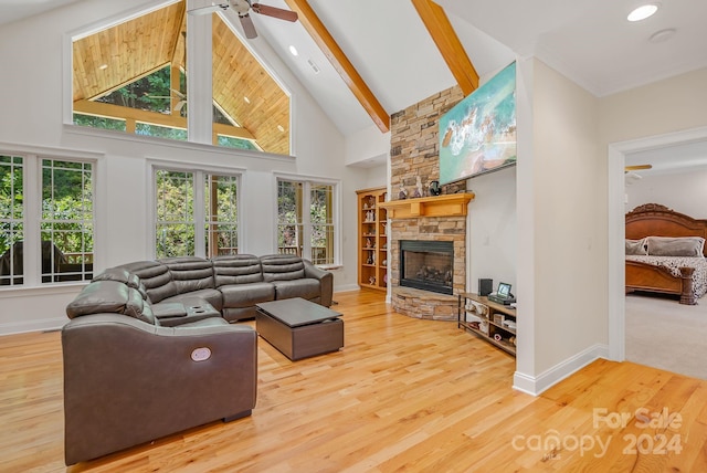 living area with beam ceiling, ceiling fan, a stone fireplace, wood finished floors, and high vaulted ceiling
