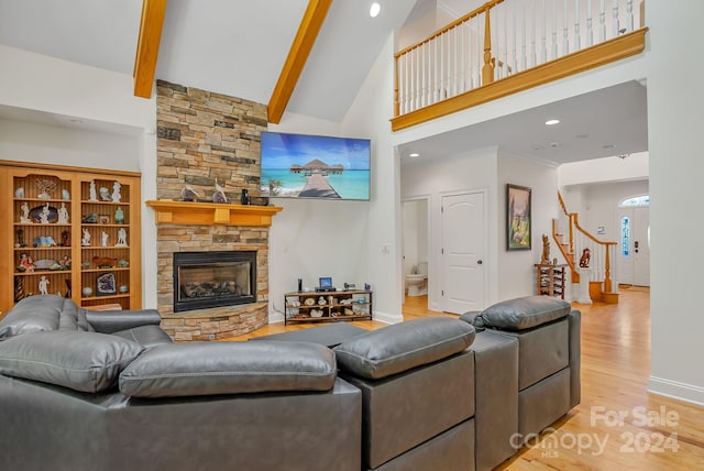 living room featuring high vaulted ceiling, light hardwood / wood-style flooring, a stone fireplace, and beam ceiling