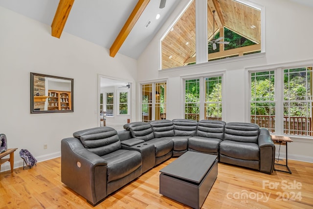 living room featuring beamed ceiling, light wood-type flooring, high vaulted ceiling, and plenty of natural light