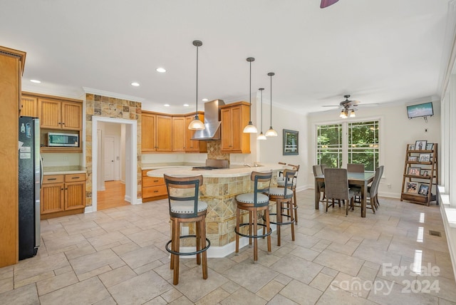 kitchen with ornamental molding, wall chimney range hood, and appliances with stainless steel finishes