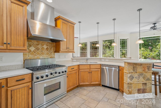 kitchen featuring a peninsula, a sink, light countertops, appliances with stainless steel finishes, and wall chimney exhaust hood