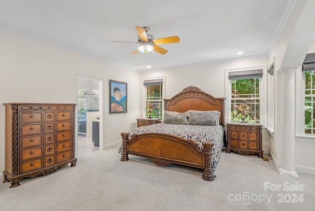 carpeted bedroom featuring ceiling fan, ensuite bath, ornate columns, and crown molding