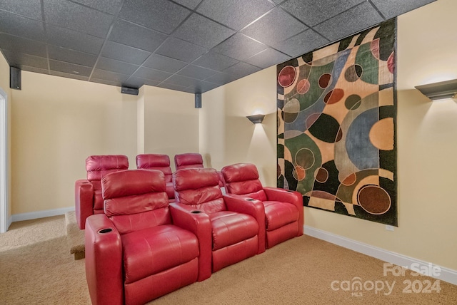 carpeted cinema room featuring a drop ceiling and baseboards