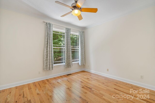 empty room with ceiling fan, light wood-type flooring, and crown molding