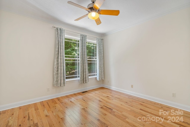 empty room featuring ceiling fan, hardwood / wood-style floors, crown molding, and baseboards