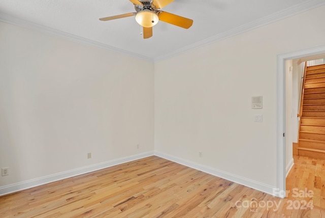 empty room featuring light wood-style flooring, a ceiling fan, baseboards, ornamental molding, and stairway