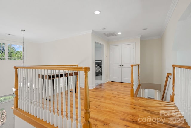 hallway with light wood-type flooring, crown molding, an upstairs landing, and recessed lighting