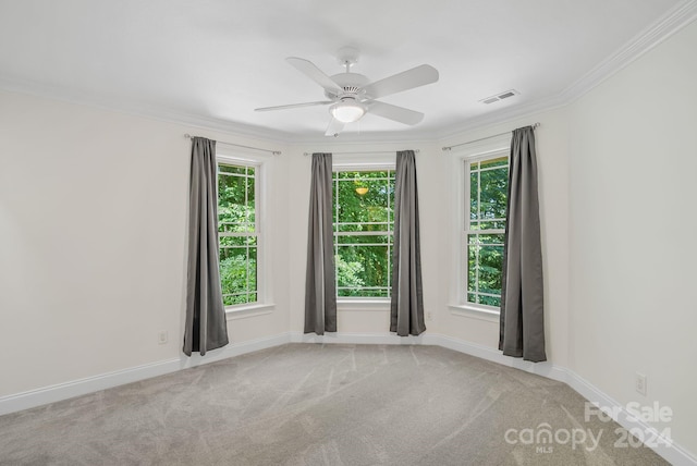 carpeted spare room with ornamental molding, visible vents, plenty of natural light, and baseboards