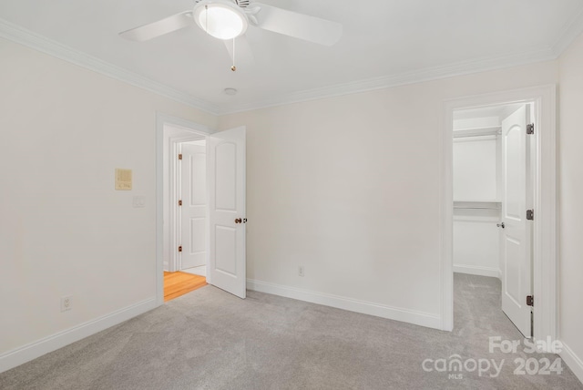 unfurnished bedroom featuring light carpet, ornamental molding, a closet, and ceiling fan