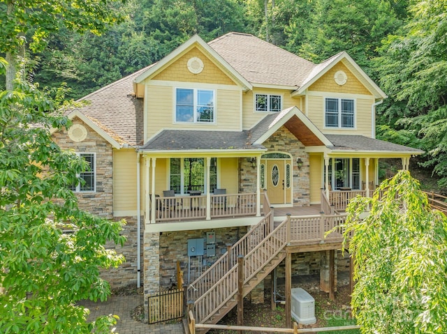 view of front of home featuring a porch, stone siding, a shingled roof, and stairs