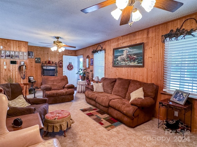 living room with ceiling fan, light colored carpet, a textured ceiling, and wood walls