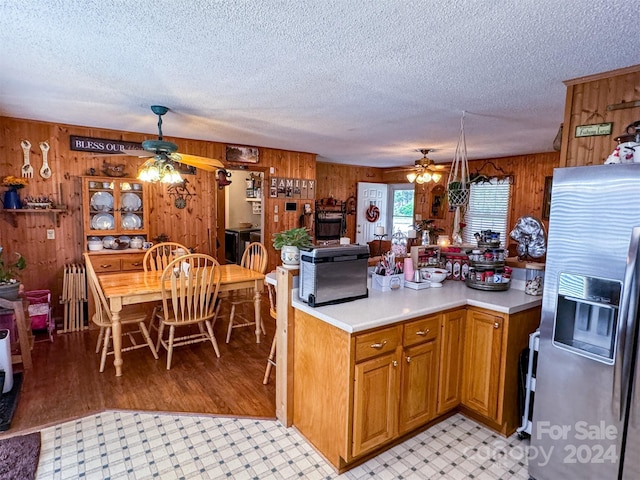 kitchen featuring a textured ceiling, stainless steel fridge, radiator, and wood walls